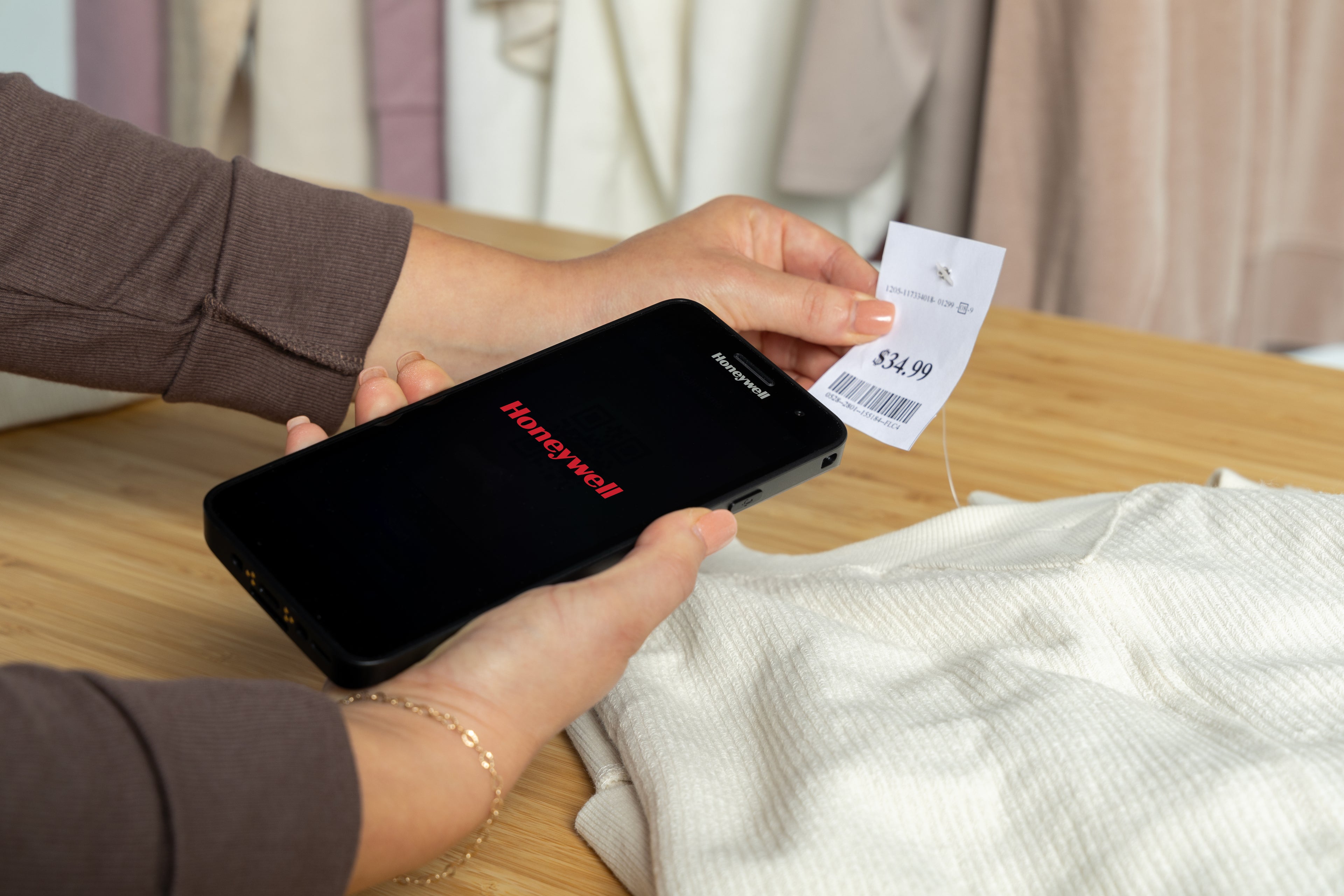 Person using a smartphone to scan a clothing tag with 'Honeywell' branding.