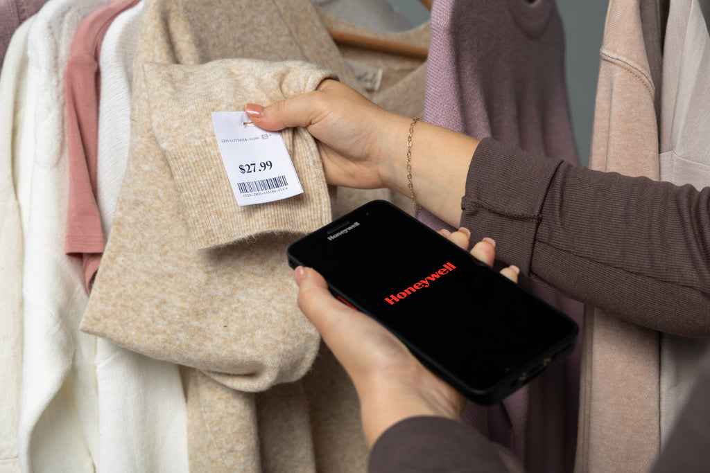 Person using a smartphone with the Honeycomb app on a clothing rack.