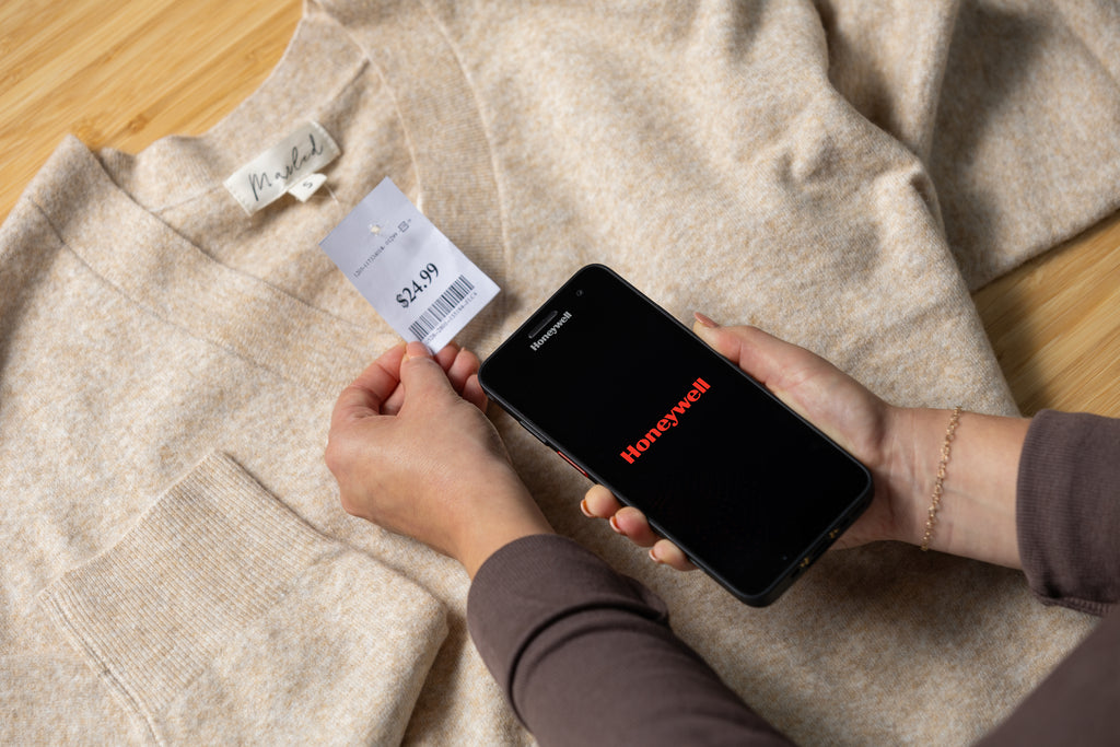 Person using a smartphone to scan a product barcode on a piece of clothing.