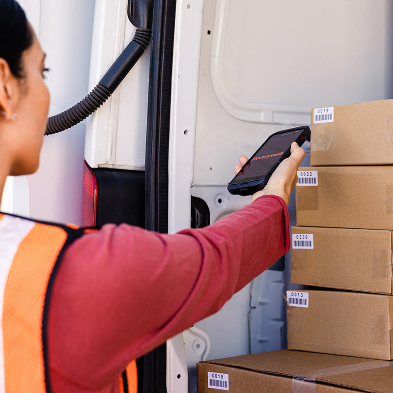 Person scanning packages with a tablet in front of a van