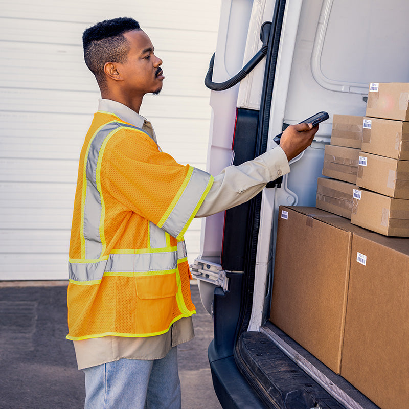Man in a high-visibility vest loading boxes into a van
